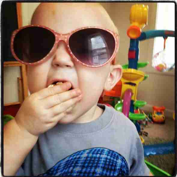Little baby wearing polka dot sunglasses and eating kettle corn popcorn.