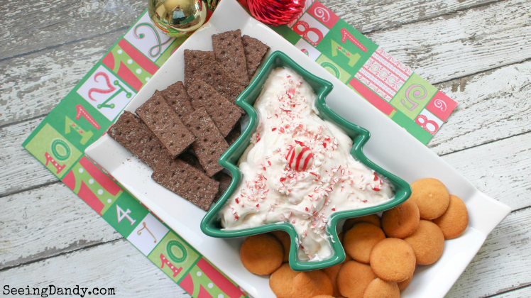 Christmas tree bowl on holiday scrapbook paper and farmhouse table with candy cane dip appetizer.