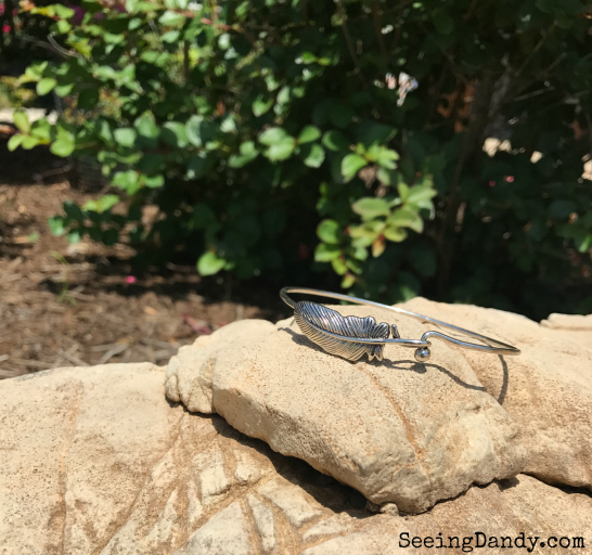 Silver feather bracelet on a rock.