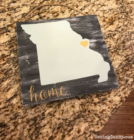 Wooden sign with Missouri outline and heart sitting on a granite countertop.