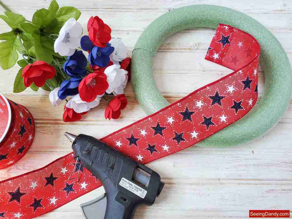 diy wreath supplies, red white blue star ribbon, patriotic poppy flowers, glue gun, green foam wreath