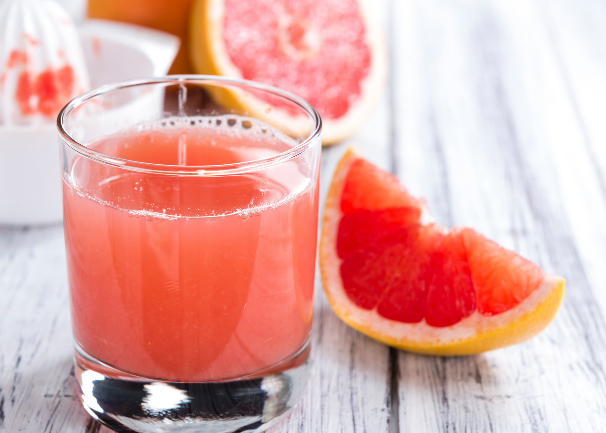 gray farmhouse table, grapefruit juicer, plastic juicer, glass of grapefruit juice