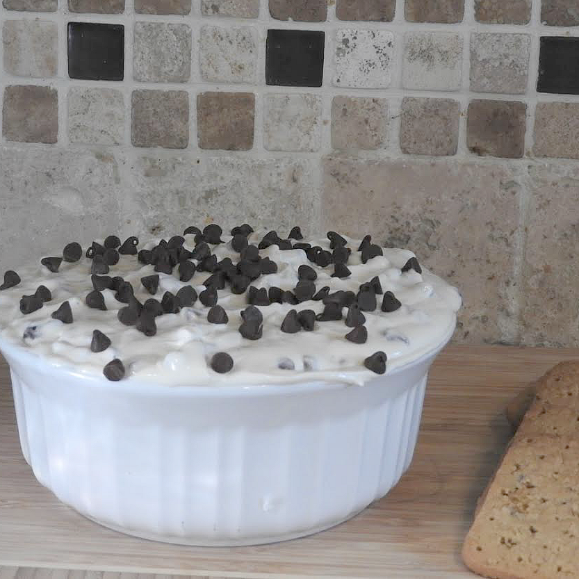 Delicious and easy to make chocolate chip cheesecake dip on wood cutting board with gluten free graham crackers.