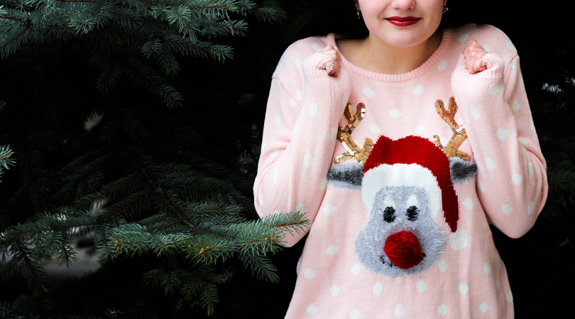 Gray reindeer ugly Christmas sweaters with pink polka dots. In front of a fir tree.