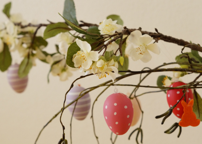 Bright color Easter eggs hung on a flowering tree branch for spring decoration.