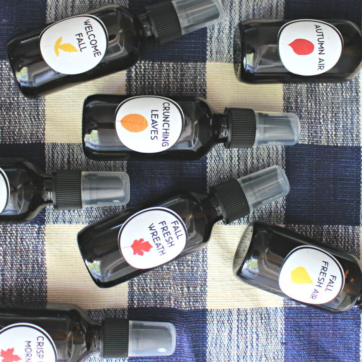 Essential oil room sprays for fall on a buffalo plaid tablecloth in blue and white.